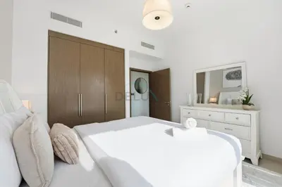 a white bedroom with a large bed and a dresser at Steps from Dubai Mall and Burj Khalifa, with Seamless Metro Access to Dubai Marina and Palm Jumeirah - Act One Act Two Tower 1, Downtown Dubai by Deluxe Holiday Homes in Dubai