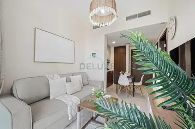 a living room with a couch and a palm tree at Located Near Dubai Mall, Burj Khalifa and Dubai Canal, with Easy Access to Dubai Metro - Vera Tower, Business Bay by Deluxe Holiday Homes in Dubai