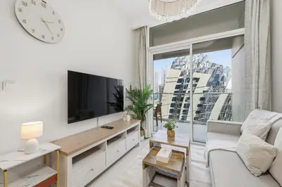 a living room with a tv and a large window at Located Near Dubai Mall, Burj Khalifa and Dubai Canal, with Easy Access to Dubai Metro - Vera Tower, Business Bay by Deluxe Holiday Homes in Dubai
