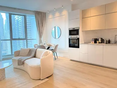 a living room with a chair and a kitchen with a table at Marina Luxury 2 Bedroom Boutique Apartment in Dubai