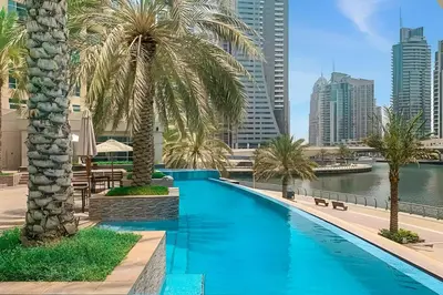 a pool with palm trees and a view of the city at High-Floor 2BR in Dubai Marina with Balcony in Dubai