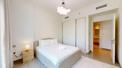 a white bedroom with a bed and a night stand at Vacationer l Infinity Pool, Beach Access l 1 Bed in Beach Vista in Dubai