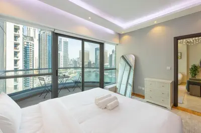 a bedroom with a large white bed and a balcony at Vacationer l 1 Bedroom Stunning Marina Skyline l Free Pool, Gym Access in Dubai