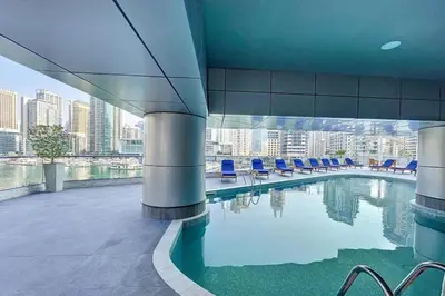 a swimming pool in a building with blue chairs at Vacationer l 1 Bedroom Stunning Marina Skyline l Free Pool, Gym Access in Dubai