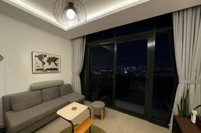a living room with a couch and a large window at Stunning 1 Bed in Meydan in Dubai