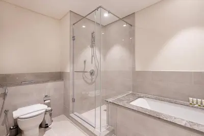 a bathroom with a shower and a toilet and a tub at Forte Tower 2 - 3 Bedroom with Maid's Room Apartment - Allsopp & Allsopp in Dubai