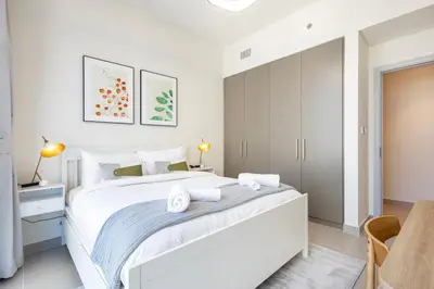 a white bedroom with a large bed with two towels at Forte Tower 2 - 3 Bedroom with Maid's Room Apartment - Allsopp & Allsopp in Dubai