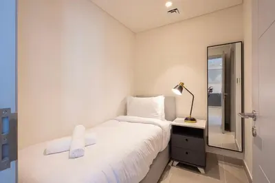 a small bedroom with a bed and a mirror at Forte Tower 2 - 3 Bedroom with Maid's Room Apartment - Allsopp & Allsopp in Dubai