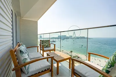 a balcony with chairs and a table and a view of the beach at Beachfront Stay with Full Sea Views, Walking Distance to The Walk, JBR Beach, and Dubai Marina - La Vie, Jumeirah Beach Residence by Deluxe Holiday Homes in Dubai