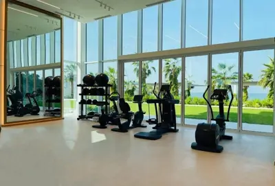 a gym with treadmills and ellipticals in a room with windows at Beachfront Stay with Full Sea Views, Walking Distance to The Walk, JBR Beach, and Dubai Marina - La Vie, Jumeirah Beach Residence by Deluxe Holiday Homes in Dubai