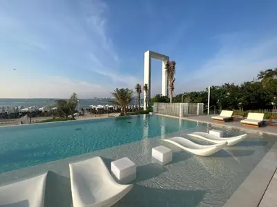 a swimming pool with white lounge chairs and the ocean at Beachfront Stay with Full Sea Views, Walking Distance to The Walk, JBR Beach, and Dubai Marina - La Vie, Jumeirah Beach Residence by Deluxe Holiday Homes in Dubai