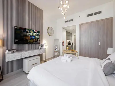a bedroom with a large white bed and a tv at Livin' Holidays - Studio - Riviera Elegance in Dubai
