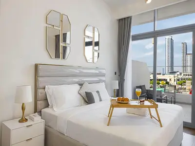 a bedroom with a bed with a table and a view at Livin' Holidays - Studio - Riviera Elegance in Dubai