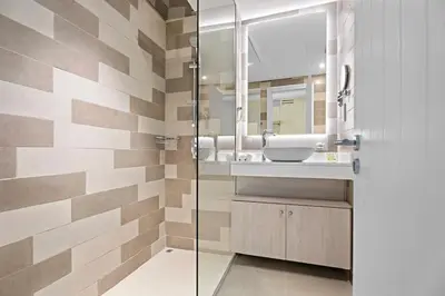 a bathroom with a sink and a glass shower at Stylish Studio with Rooftop Pool on the Palm in Dubai