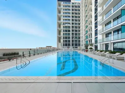 a large swimming pool in the middle of a building at Chic Studio with Balcony, Gym & Pools in JVC in Dubai