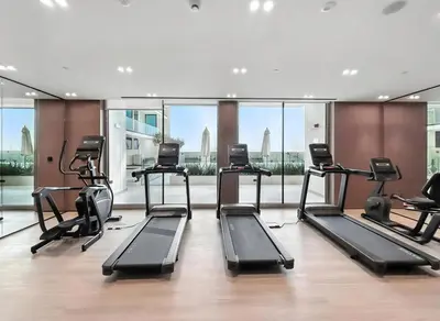a gym with treadmills and elliptical machines at Chic Studio with Balcony, Gym & Pools in JVC in Dubai