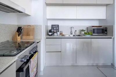 a white kitchen with white cabinets and a microwave at Frank Porter - Marina Vista Tower 1 in Dubai