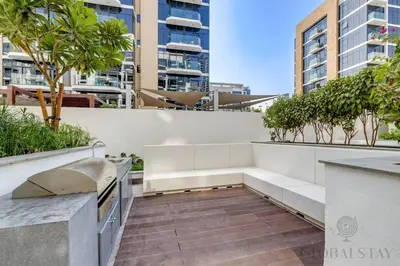 a balcony with a bench and trees and buildings at GlobalStay 1 Bedroom Apartment for 4 Guests Azizi Riviera 42 Dubai in Dubai