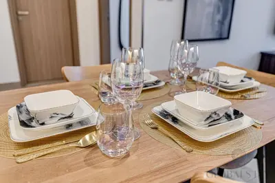 a wooden table with wine glasses and plates on it at GlobalStay 1 Bedroom Apartment for 4 Guests Azizi Riviera 42 Dubai in Dubai