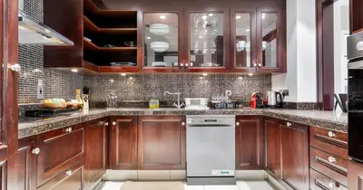 a kitchen with wooden cabinets and a white dishwasher at Downtown 2BHK Iconic Burj Khalifa Views in Dubai