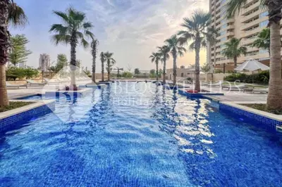 a swimming pool with palm trees in a resort at Bloomfields Cozy Stu Damac Ghalia Jvc in Dubai