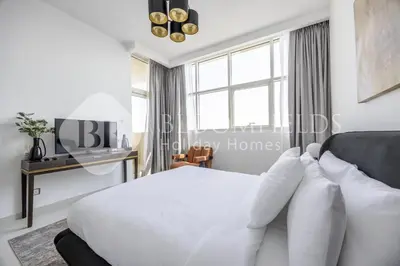 a white bedroom with a bed and a window at Bloomfields Cozy Stu Damac Ghalia Jvc in Dubai