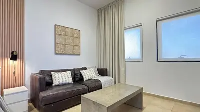 a living room with a brown couch and a table at Cozy & Stylish Studio in Silicon Oasis in Dubai