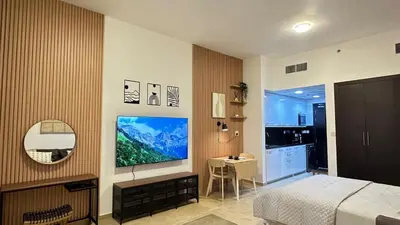 a bedroom with a bed and a television on a wall at Cozy & Stylish Studio in Silicon Oasis in Dubai