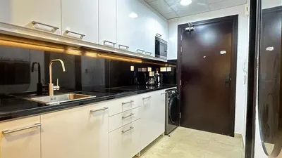 a large kitchen with a sink and a refrigerator at Cozy & Stylish Studio in Silicon Oasis in Dubai