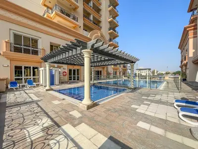 a swimming pool with a pergola next to a building at Splendid Studio near Canal & famous Golf Clubs in Dubai