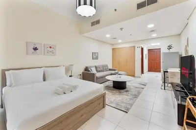 a bedroom with a large bed and a living room at Splendid Studio near Canal & famous Golf Clubs in Dubai