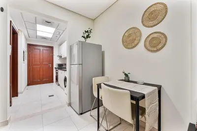a kitchen with a table and a refrigerator at Splendid Studio near Canal & famous Golf Clubs in Dubai