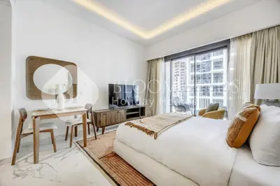 a white bedroom with a desk and a large window at Bloomfields Lumière Stu Azizi Riviera in Dubai