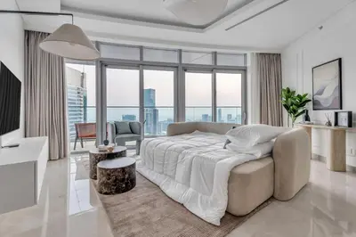 a white bedroom with a large bed and large windows at GuestReady - High-Floor 2BR | Canal and City View in Dubai