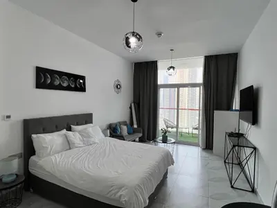 a bedroom with a white bed and a large window at Binghatti Millennium Studio Apartment in Dubai