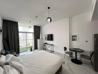 a bedroom with a bed and a table and chairs at Binghatti Millennium Studio Apartment in Dubai