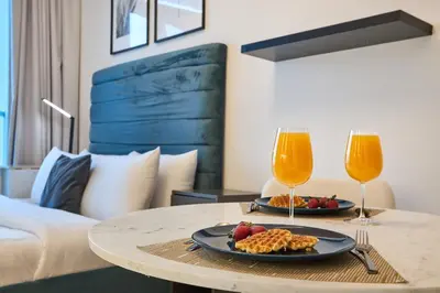 a table with a plate of food and two glasses of orange juice at Modern Studio in Studio One Tower, Dubai Marina in Dubai