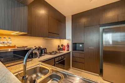 a kitchen with wooden cabinets and a stainless steel refrigerator at Central 2BR Downtown Views EB in Dubai