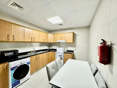 a kitchen with a white table and a red fire extinguisher at Perfect choice for a big family in Dubai
