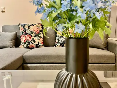 a vase with blue flowers in a living room at Karama pretty unit near metro in Dubai