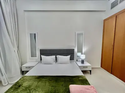 a white bedroom with a bed and two windows at Not far from metro Spacious in Dubai