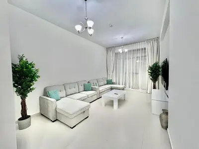 a white living room with a couch and a table at Not far from metro Spacious in Dubai