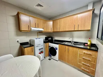 a small kitchen with wooden cabinets and a dishwasher at Not far from metro Spacious in Dubai