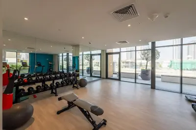 a gym with treadmills and cardio equipment in a building at Stylish Studio with Gym & Pool in Azizi Riviera in Dubai