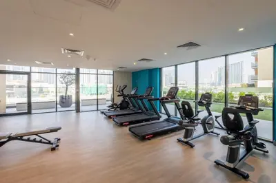a gym with rows of treadmills and elliptical machines at Stylish Studio with Gym & Pool in Azizi Riviera in Dubai