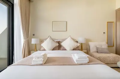 a bedroom with a large white bed with two lamps at Stylish Studio with Gym & Pool in Azizi Riviera in Dubai
