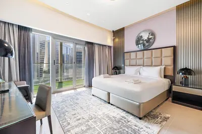a hotel room with a bed and a desk and windows at Beautiful Canal View Majestine Damac in Dubai