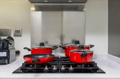 three red pots on a stove in a kitchen at Beautiful Canal View Majestine Damac in Dubai