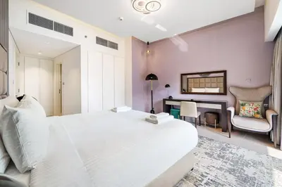 a bedroom with a large white bed and a fireplace at Beautiful Canal View Majestine Damac in Dubai