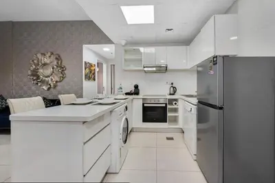 a kitchen with white cabinets and a stainless steel refrigerator at Spacious 2 Bedroom Apartment in JBR in Dubai